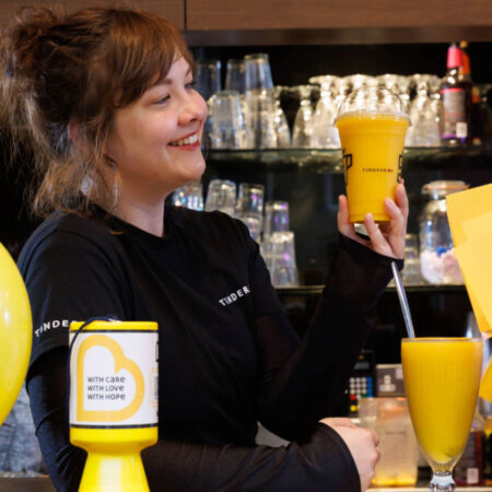 Tinderbox Employee holding new Mango Cooler drink made in collaboration with Matthew Algie and Tinderbox 