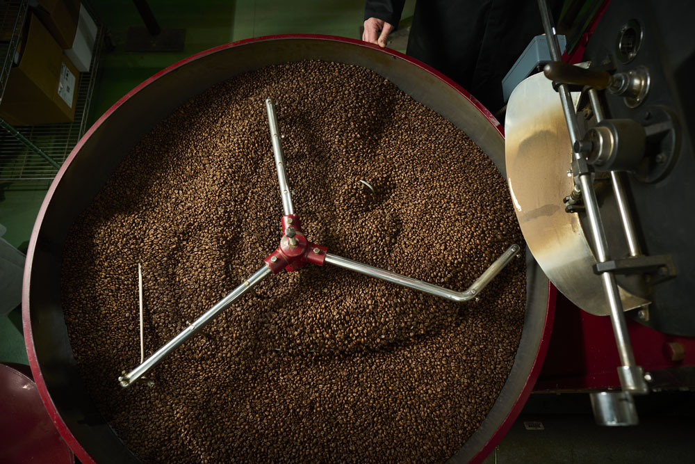 Birds-eye view photo of a traditional gas-fired small batch coffee roaster full of freshly roasted coffee beans