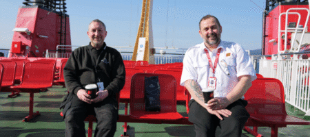 CalMac Employee and Matthew Algie employee sitting side by side with a bag of Matthew Algie coffee sitting in between them.